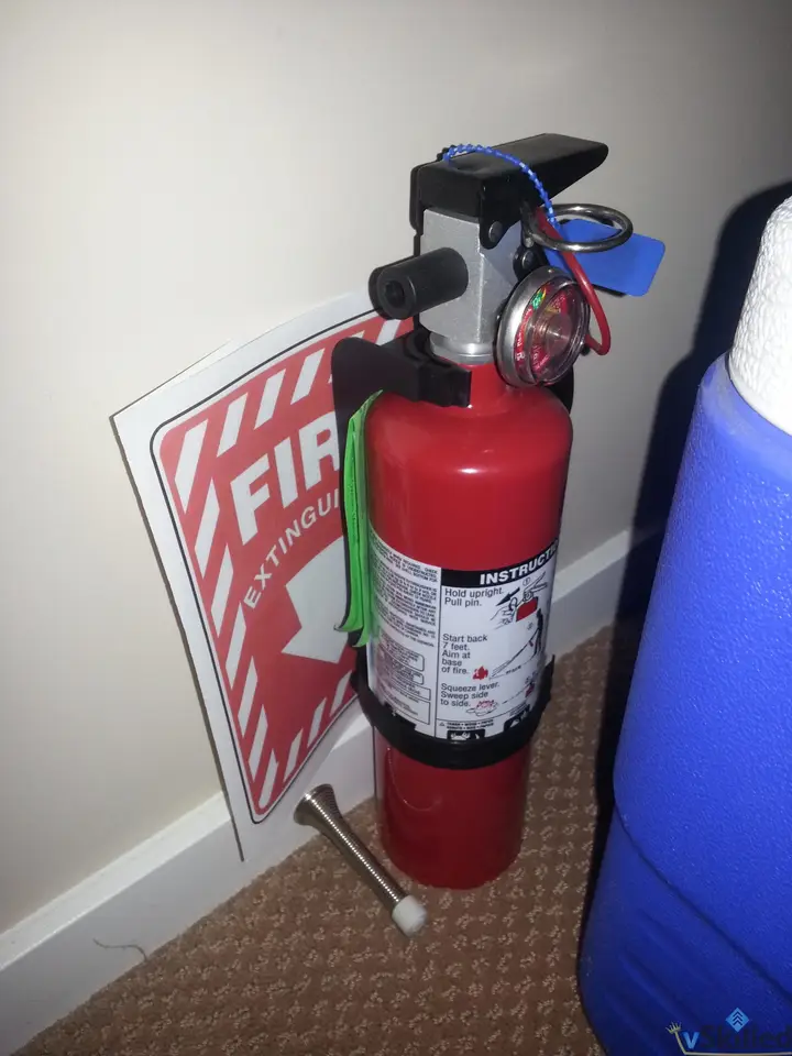 Red fire extinguisher secured beside a blue cooler