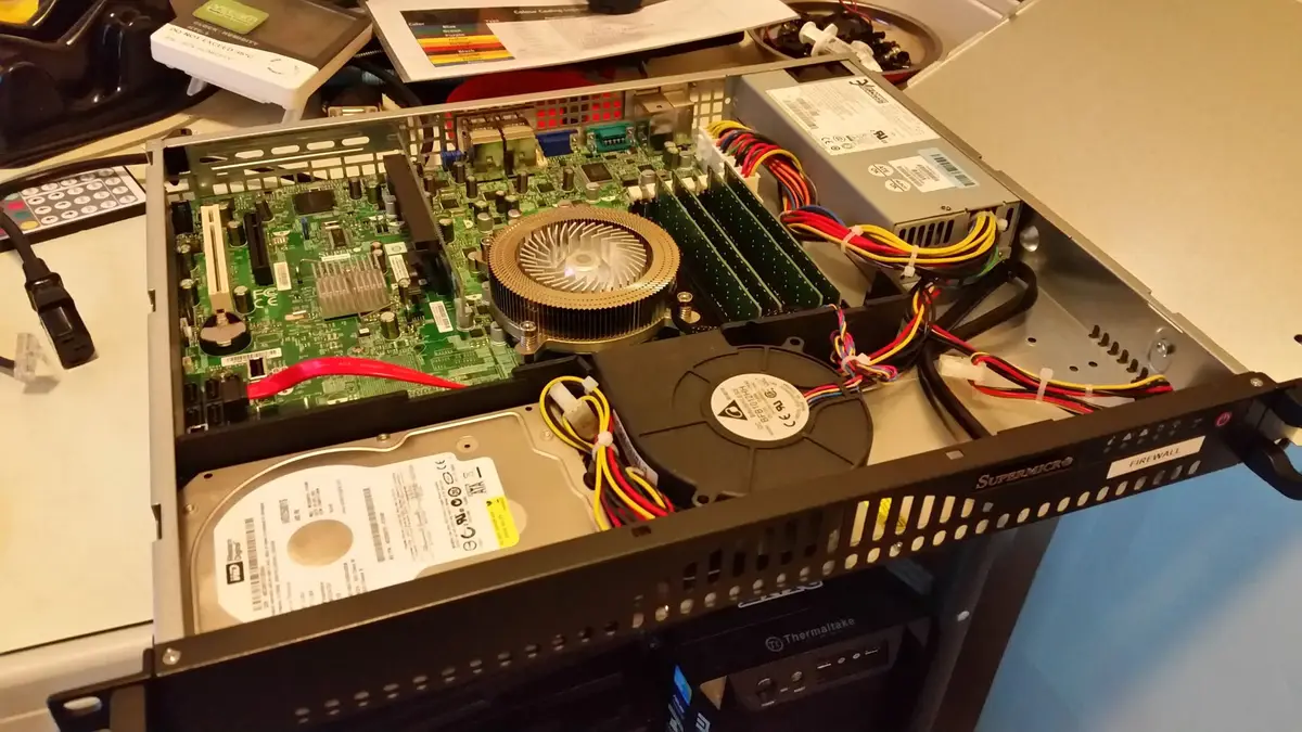 Open Supermicro 1U firewall showing its motherboard, low-profile CPU cooler and hard drive