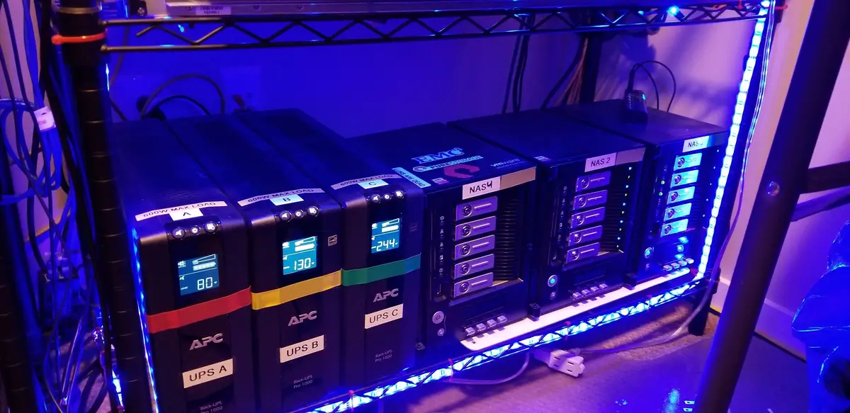 Home lab storage shelf with three Thecus NAS units and three UPS batteries