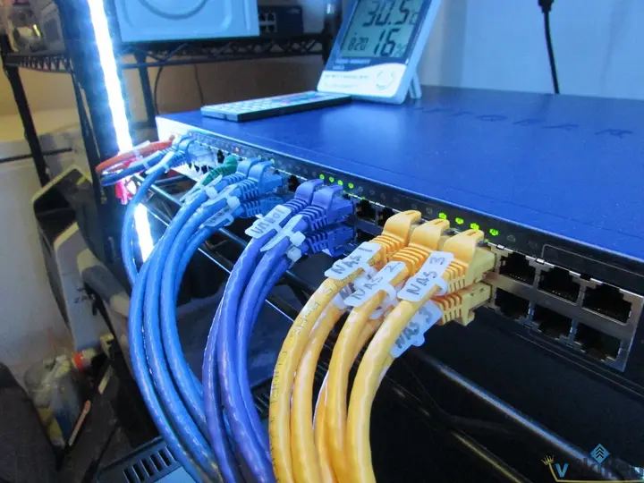 Netgear core switch with labeled blue and yellow Ethernet cables