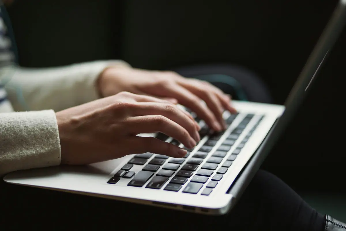 Hands typing on a laptop keyboard at a desk