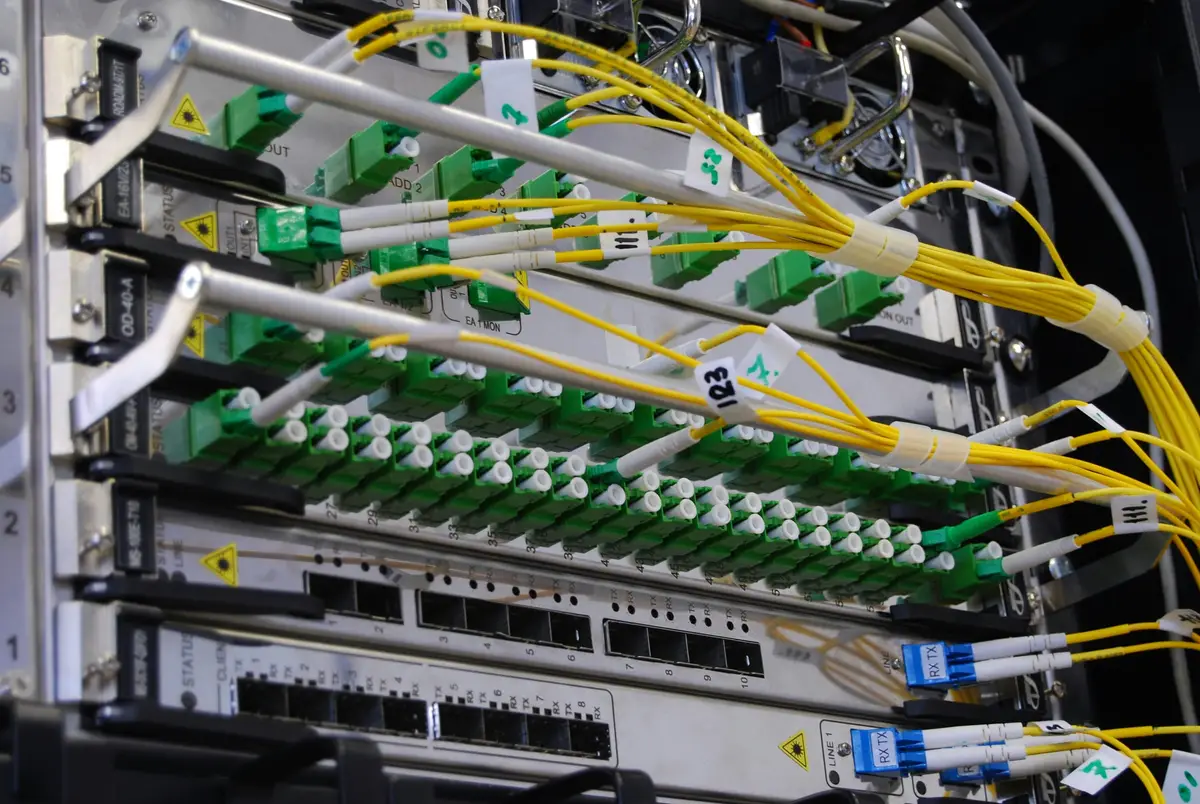 Green fibre connectors and yellow cables inside a network rack