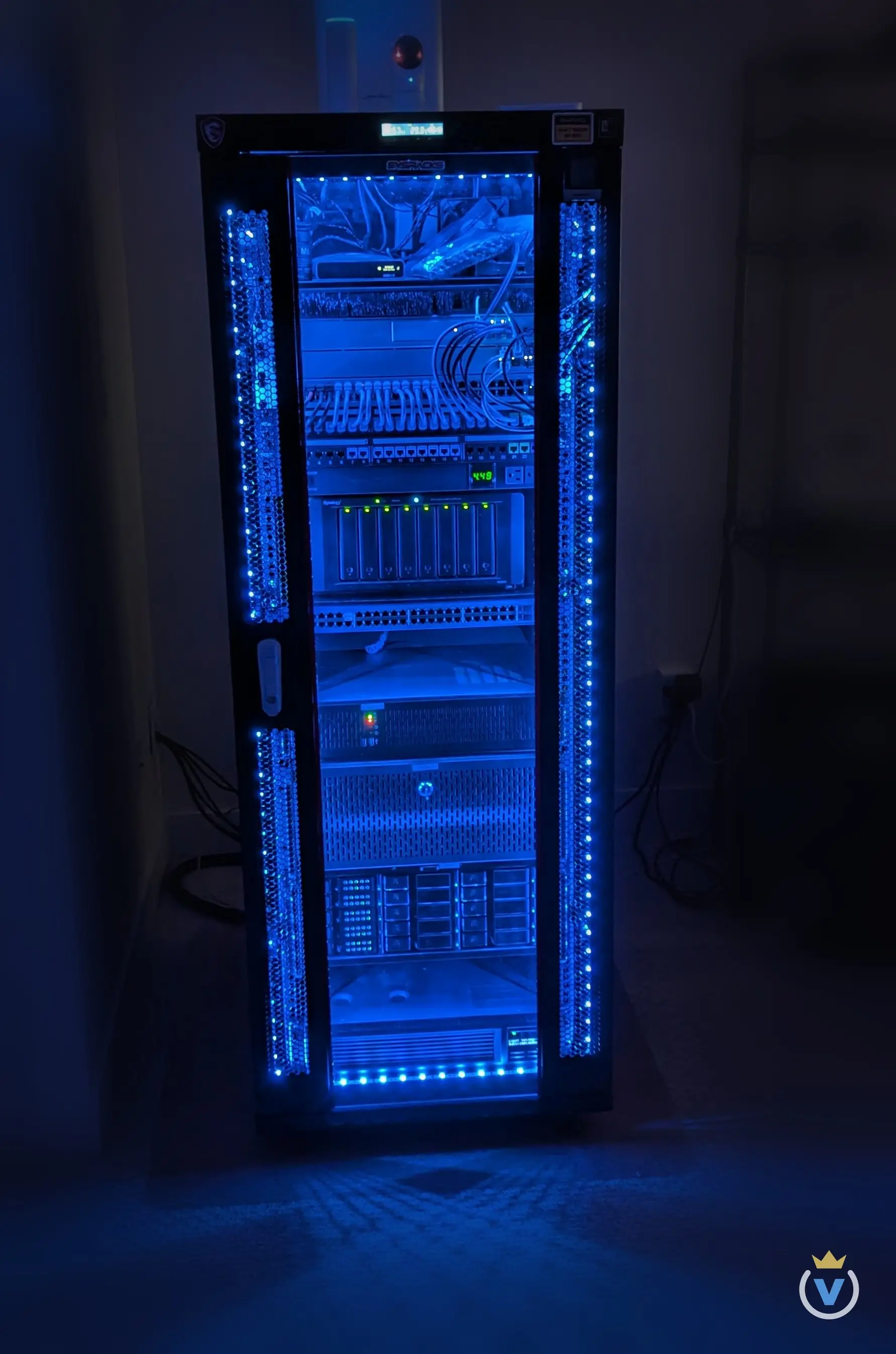 The SysRacks 32U enclosure lit blue, glass door closed, every unit from the UniFi switching down to the UPS visible.