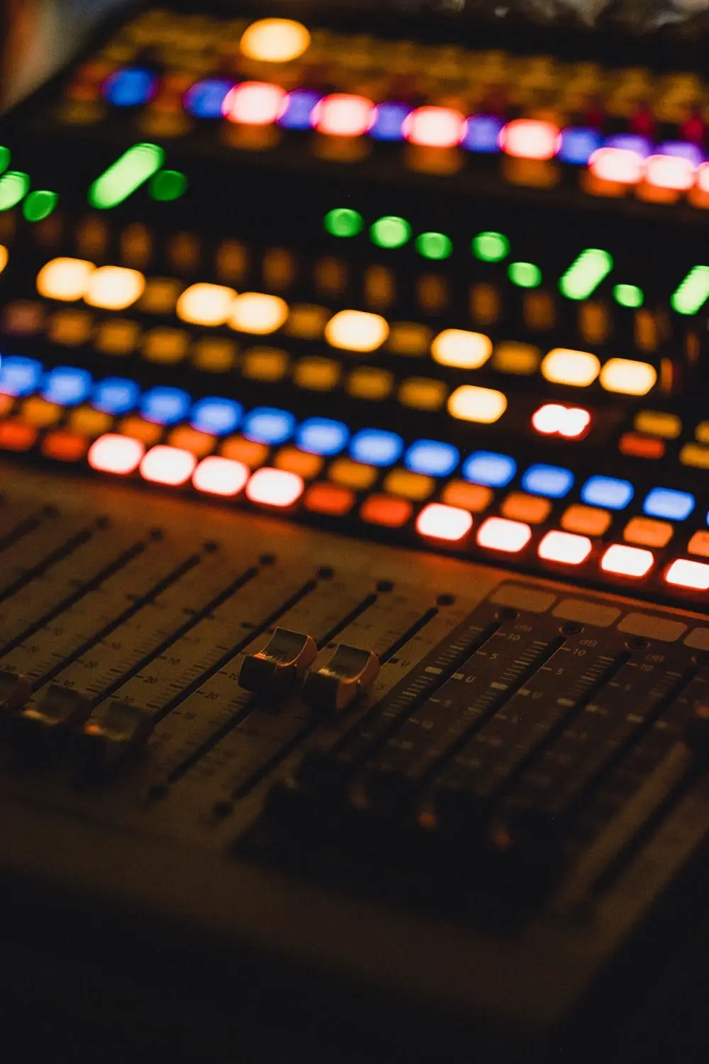 Audio mixing console with illuminated buttons and faders