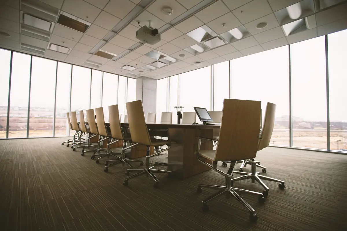 Empty meeting room with a long table and rows of chairs