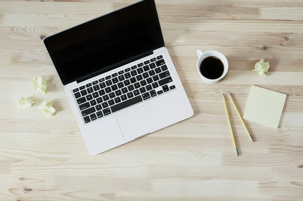 Laptop, notebook and coffee arranged on a wooden desk