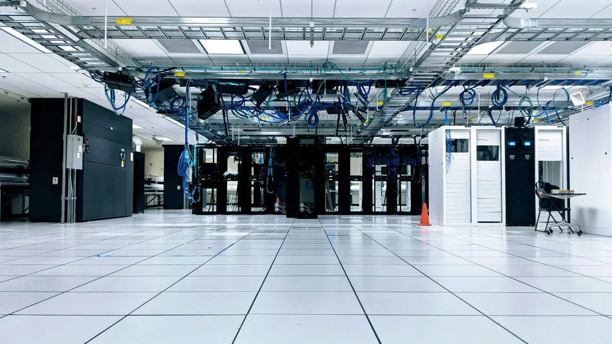 Data centre cabinets beneath overhead blue cabling